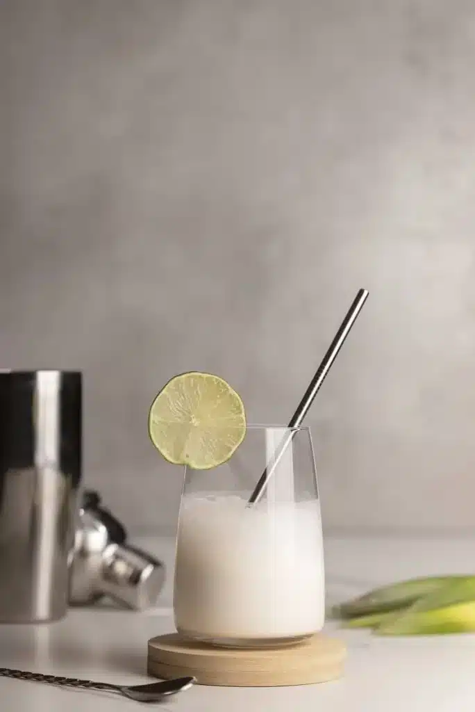 caipirinha de leite condensado em cima de mesa com coqueteleira e canudo