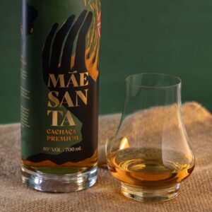 glass filled with a bottle of Mãe Santa cachaça